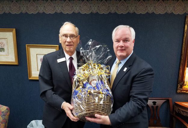 Forcht Broadcasting: two men in suits holding a basket smiling at the camera