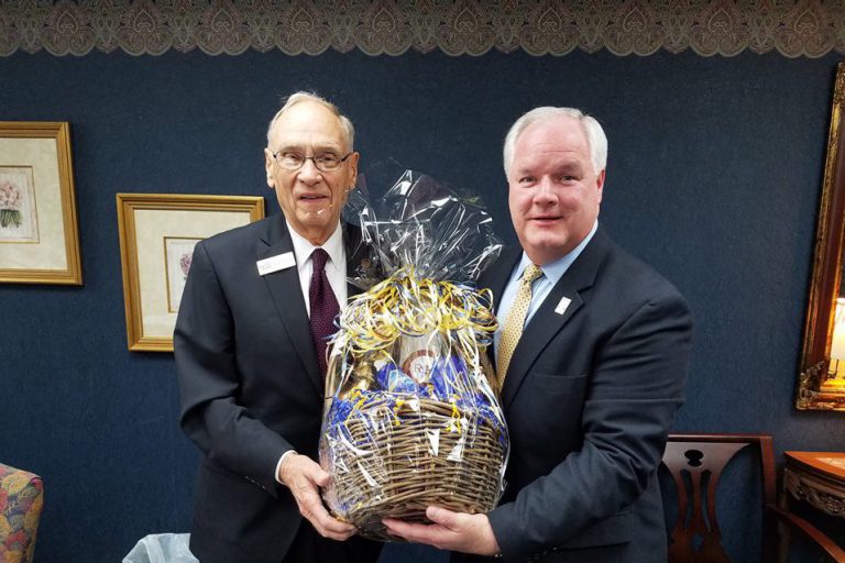 Forcht Broadcasting: two men in suits holding a basket smiling at the camera