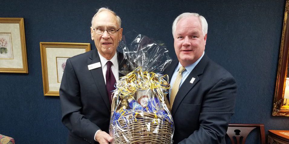 Forcht Broadcasting: two men in suits holding a basket smiling at the camera