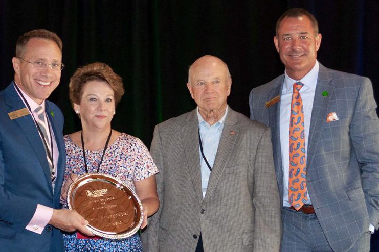 Small Business: three men and a woman smiling at the camera holding a trophy