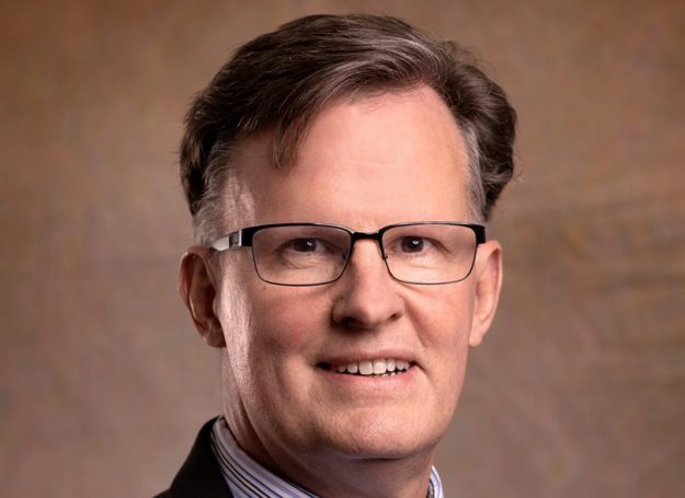 President: a man in a suit smiling at the camera